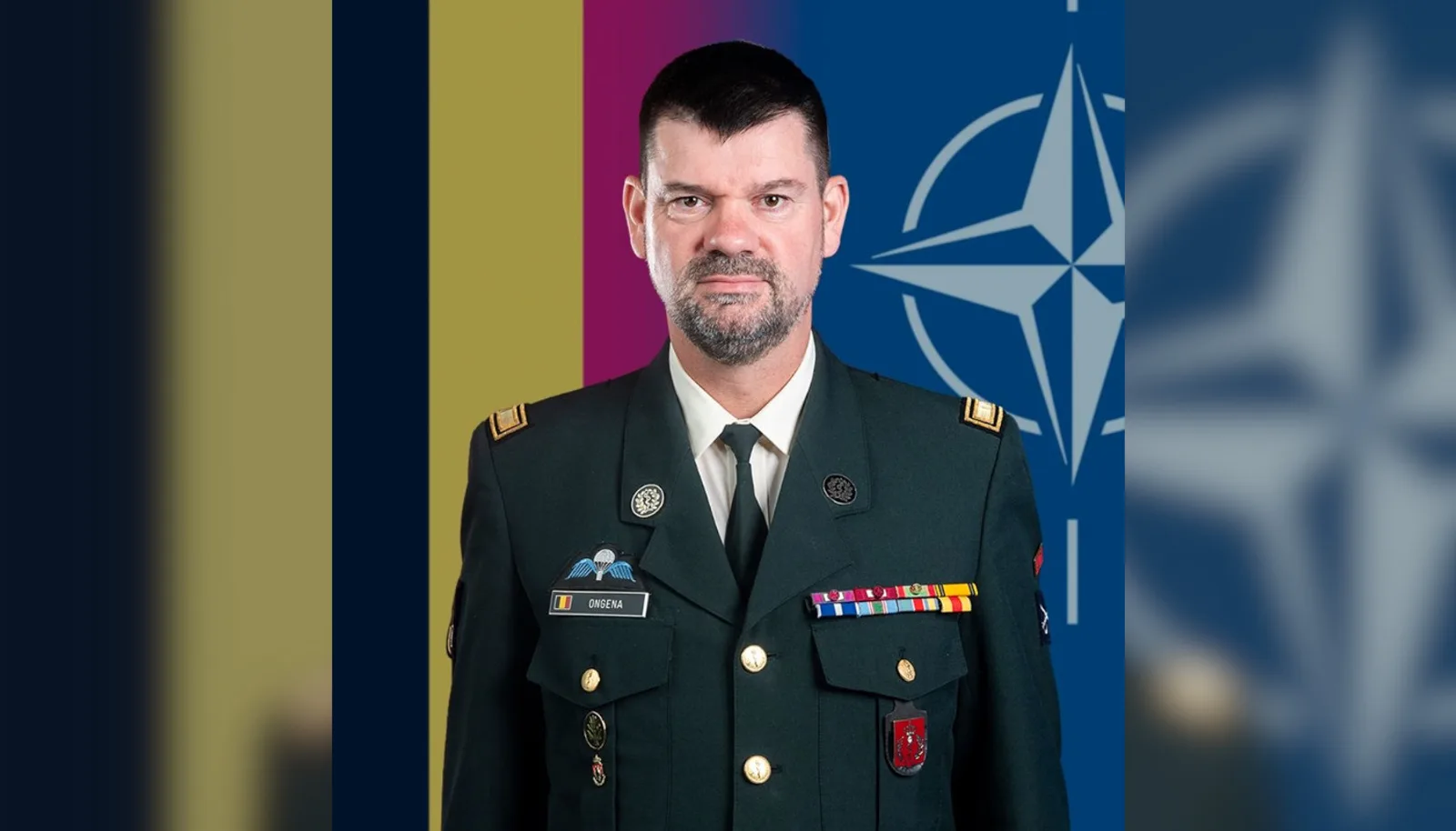 Generalmajor Marc Ongena, Vizevorsitzender des NATO-Ausschusses der Leiter der Sanitätsdienste (COMEDS), in belgischer Dienstuniform. Im Hintergrund sind die Nationalflagge Belgiens und die Flagge der NATO dargestellt.