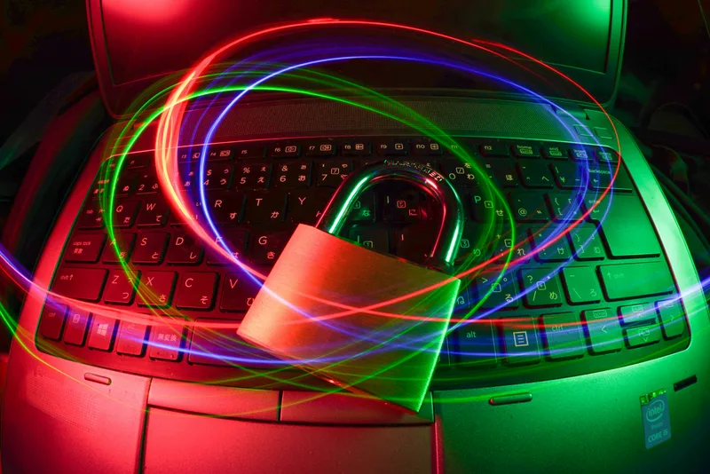 Geschlossenes Vorhängeschloss auf einer Laptop-Tastatur mit Intel-Aufkleber vor farbigen Lichteffekten