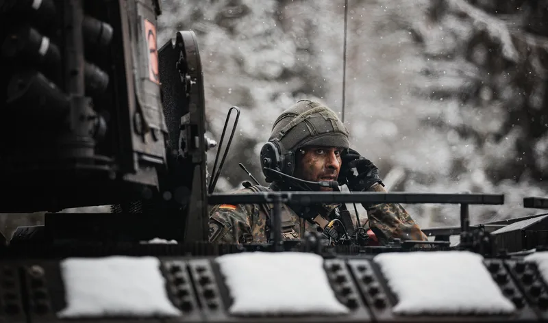 Bundeswehr-Soldat mit Sprechhaube blickt bei Winterwetter aus der Luke eines Schützenpanzers Puma
