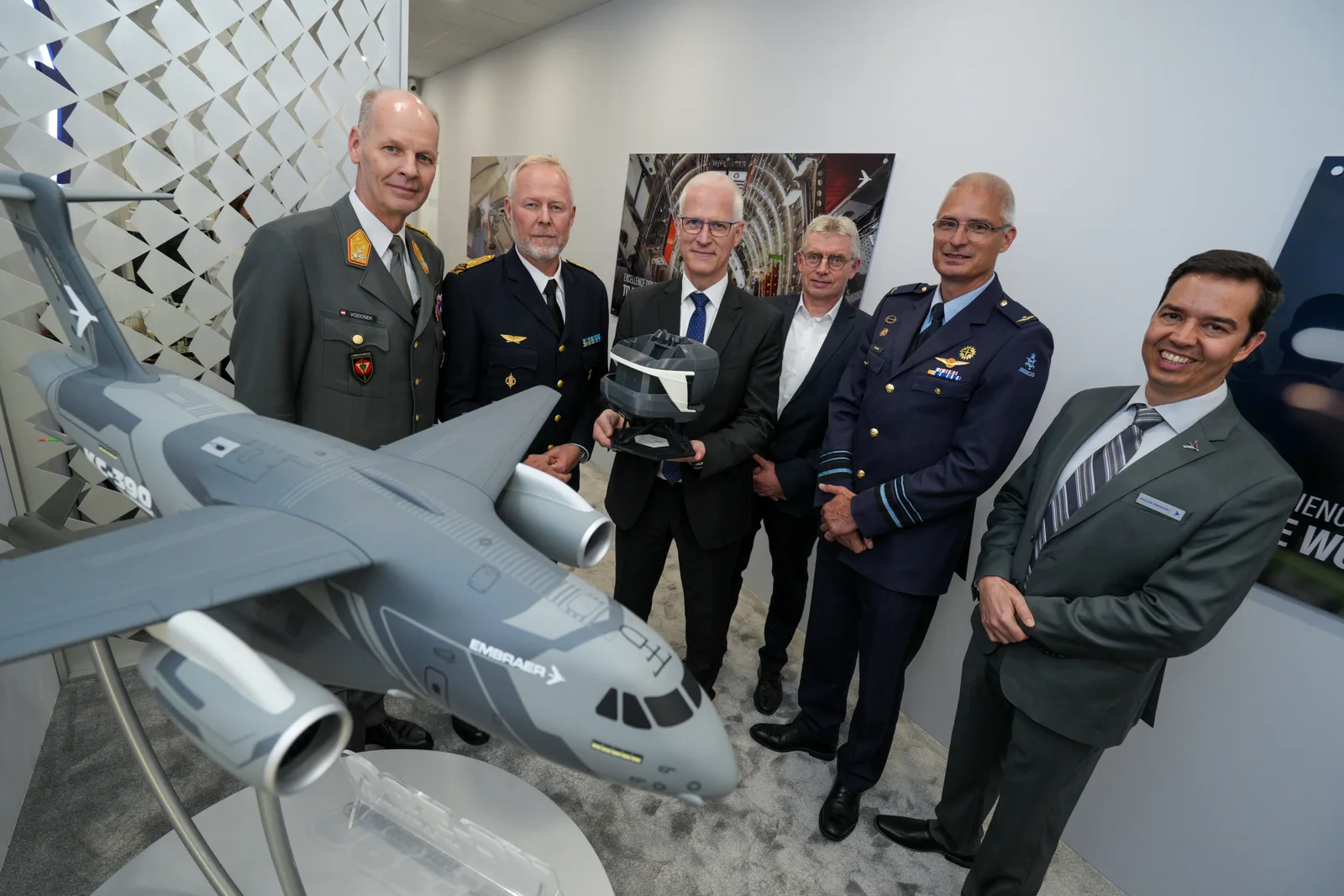 Die österreichischen und schwedischen Streitkräfte erhalten ein Modell des Trainingsgeräts für das Transportflugzeug Embraer KC-390 in Händen.