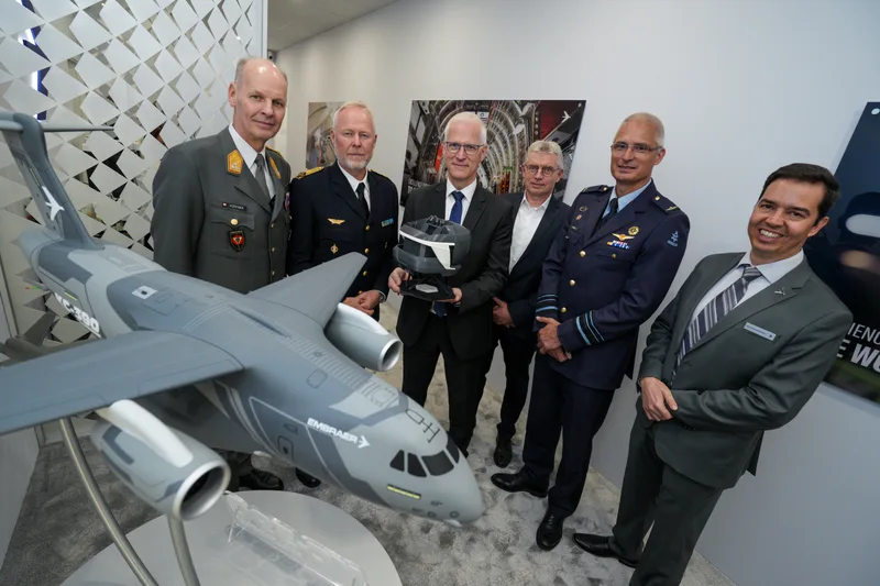 Die österreichischen und schwedischen Streitkräfte erhalten ein Modell des Trainingsgeräts für das Transportflugzeug Embraer C-390 in Händen.