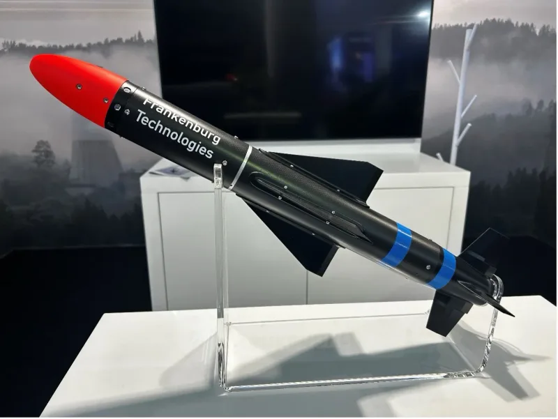 Modell eines schwarzen Flugkörpers von Frankenburg Technologies mit roter Spitze auf einem Acrylhalter bei einer Ausstellung