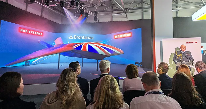 Offizier in Uniform spricht bei einer BAE Systems Präsentation vor Fachpublikum vor einer Leinwand mit der Drohne Brontanax