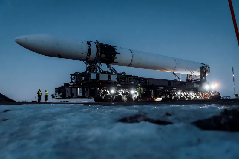 Die Trägerrakete „Spectrum“ des Herstellers Isar Aerospace wird auf einem mehrachsigen Spezialtransporter bei Dämmerung transportiert.