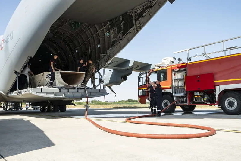 Einsatzkräfte befüllen einen im Airbus A400M der Luftwaffe installierten Löschwassertank über ein Feuerwehrfahrzeug von Sides
