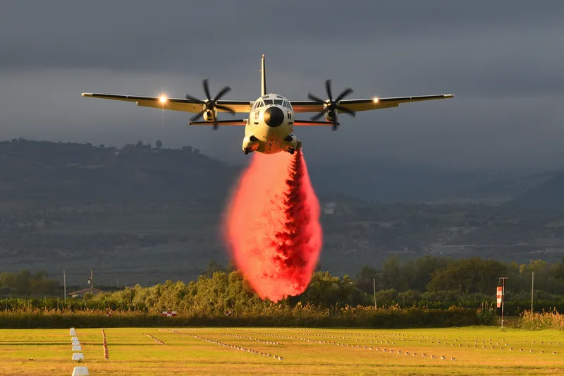 Transportflugzeug Leonardo C-27J wirft während eines Testflugs rotes Löschmittel mittels MAFFS-System über einem Flugplatz ab