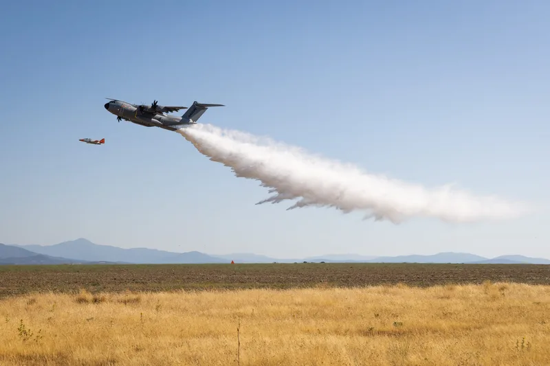 Airbus A400M wirft bei einem Brandbekämpfungstest in Spanien eine große Wassermenge ab, während ein Begleitflugzeug im Hintergrund fliegt