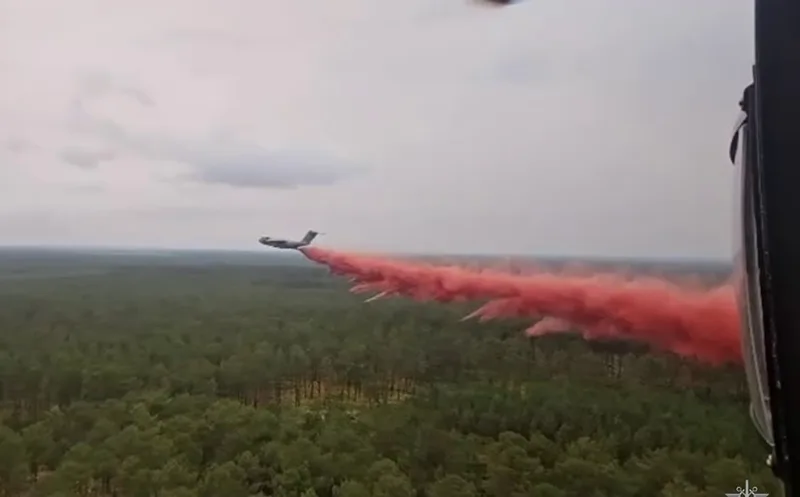 Airbus A400M der Luftwaffe wirft im Tiefflug rotes Löschmittel über einem Waldgebiet ab