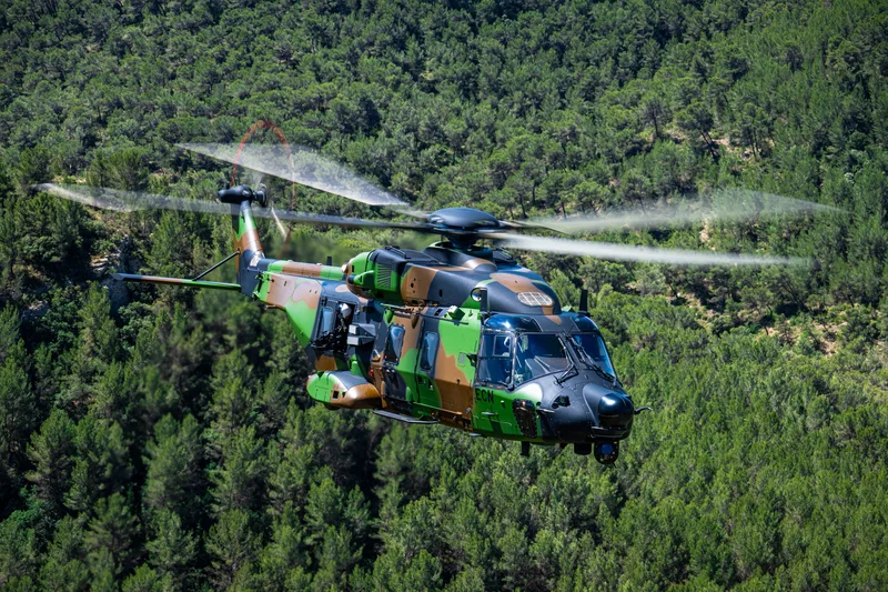 Airbus liefert ersten für Spezialeinsätze konzipierten NH90 Standard 2 an Frankreich aus  Transporthubschrauber NH90 der Luftwaffe im Tiefflug über einem Waldgebiet mit geöffneter Seitentür und Bordwaffe