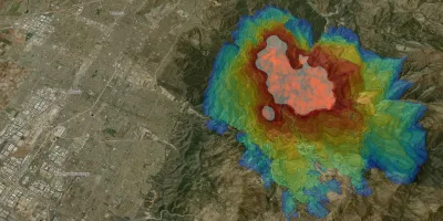 Eine satellitengestützte Geländekarte zeigt die digitale Simulation der Ausbreitung eines Waldbrandes in einer Gebirgsregion östlich von Los Angeles. Die farbigen, konzentrischen Linien markieren die zeitliche Entwicklung des Feuers nahe den US-amerikanischen Städten Pomona, Ontario und Rancho Cucamonga.