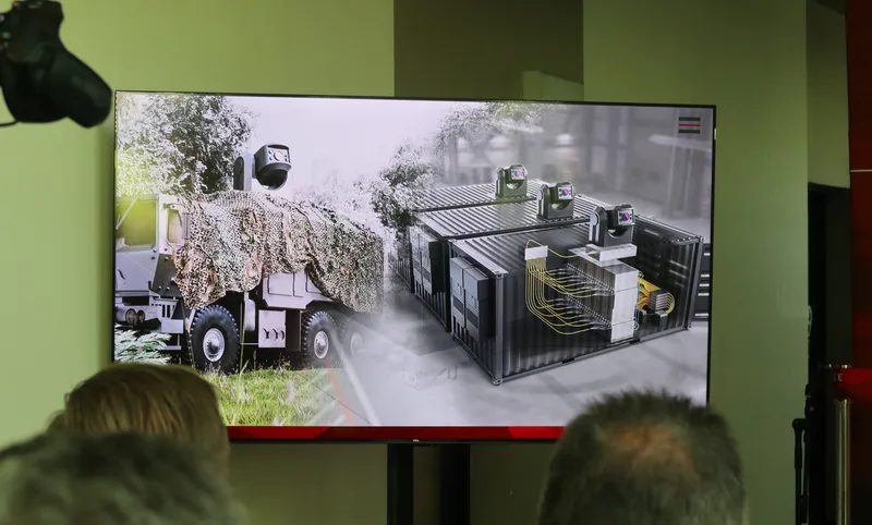 Bildschirm mit schematischer Darstellung eines Rheinmetall-Hochenergielaser-Waffensystems auf Militär-LKW und in Containern