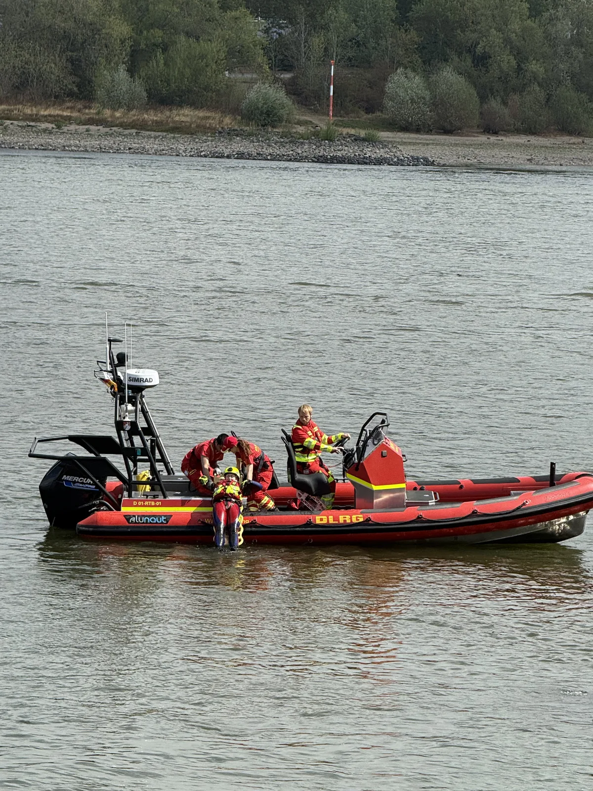 Einsatzkräfte der Deutschen Lebens-Rettungs-Gesellschaft (DLRG) nehmen während einer Übung eine Person aus dem Wasser an Bord eines Rettungsbootes des Herstellers Alunaut auf. Das Einsatzboot ist mit einem Mercury-Außenbordmotor sowie einer Radarantenne von Simrad ausgerüstet.