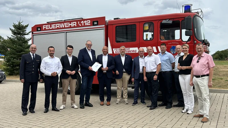 Vertreter von Politik und Freiwilliger Feuerwehr Gudensberg bei der Übergabe eines Förderbescheids vor einem Löschfahrzeug