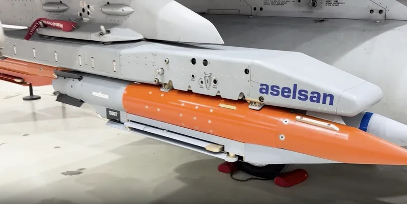 Präzisionsgelenkte Munition von Aselsan mit orangefarbener Testlackierung an der Waffenstation eines Kampfflugzeugs montiert