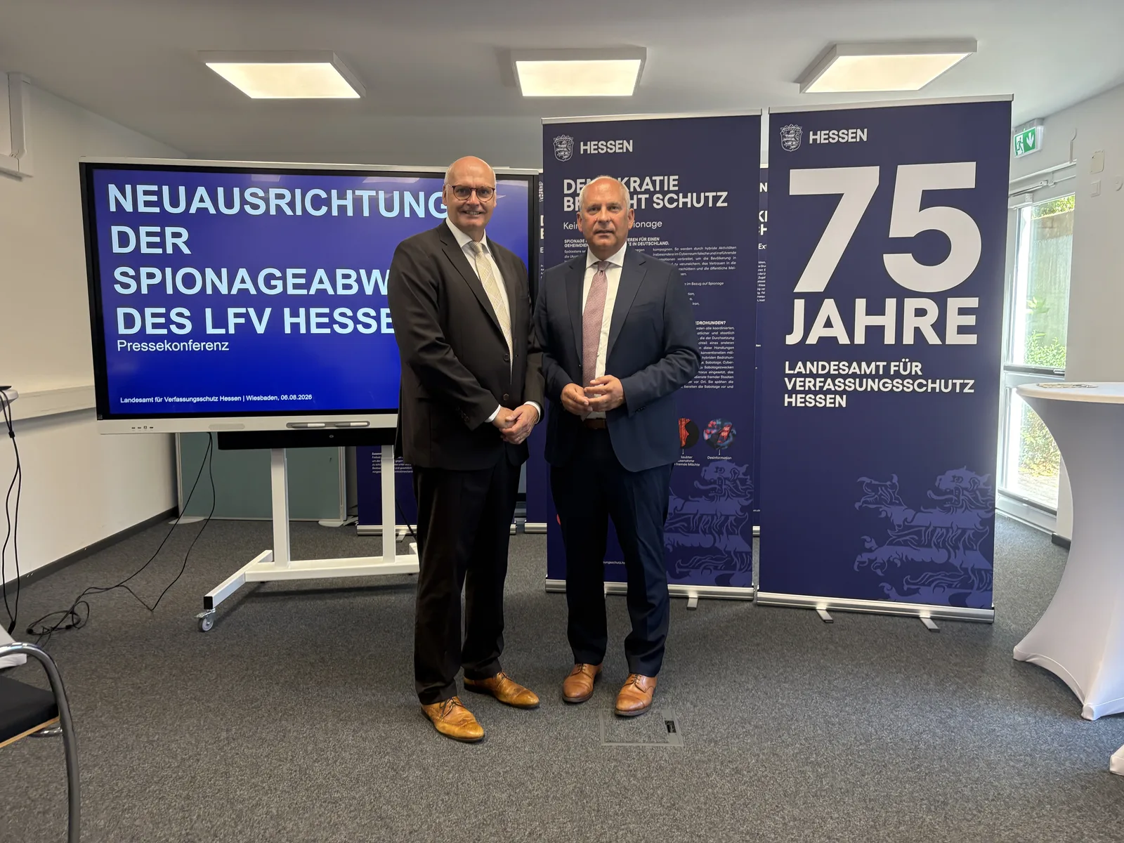 Der hessische Innenminister Roman Poseck (rechts) und der Präsident des Landesamtes für Verfassungsschutz Hessen, Bernd Öger, stehen vor einem Präsentationsbildschirm und Informationsbannern bei einer Pressekonferenz zur Neuausrichtung der Spionageabwehr in Wiesbaden.