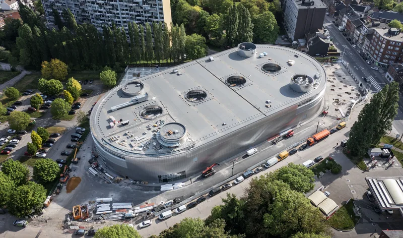 Luftaufnahme der im Bau befindlichen Aerospacelab-Satellitenfabrik mit ovalem Gebäude und Baustellenfahrzeugen in der Umgebung