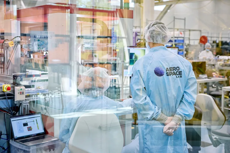 Zwei Mitarbeiter in Reinraumkleidung arbeiten an einem Bildschirmarbeitsplatz im Reinraum von Aerospacelab