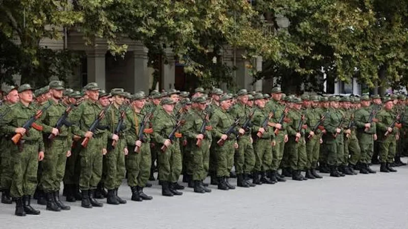 Soldaten in grünem Digitaltarn-Feldanzug stehen mit Kalaschnikow-Sturmgewehren in Formation vor einem Gebäude und Bäumen