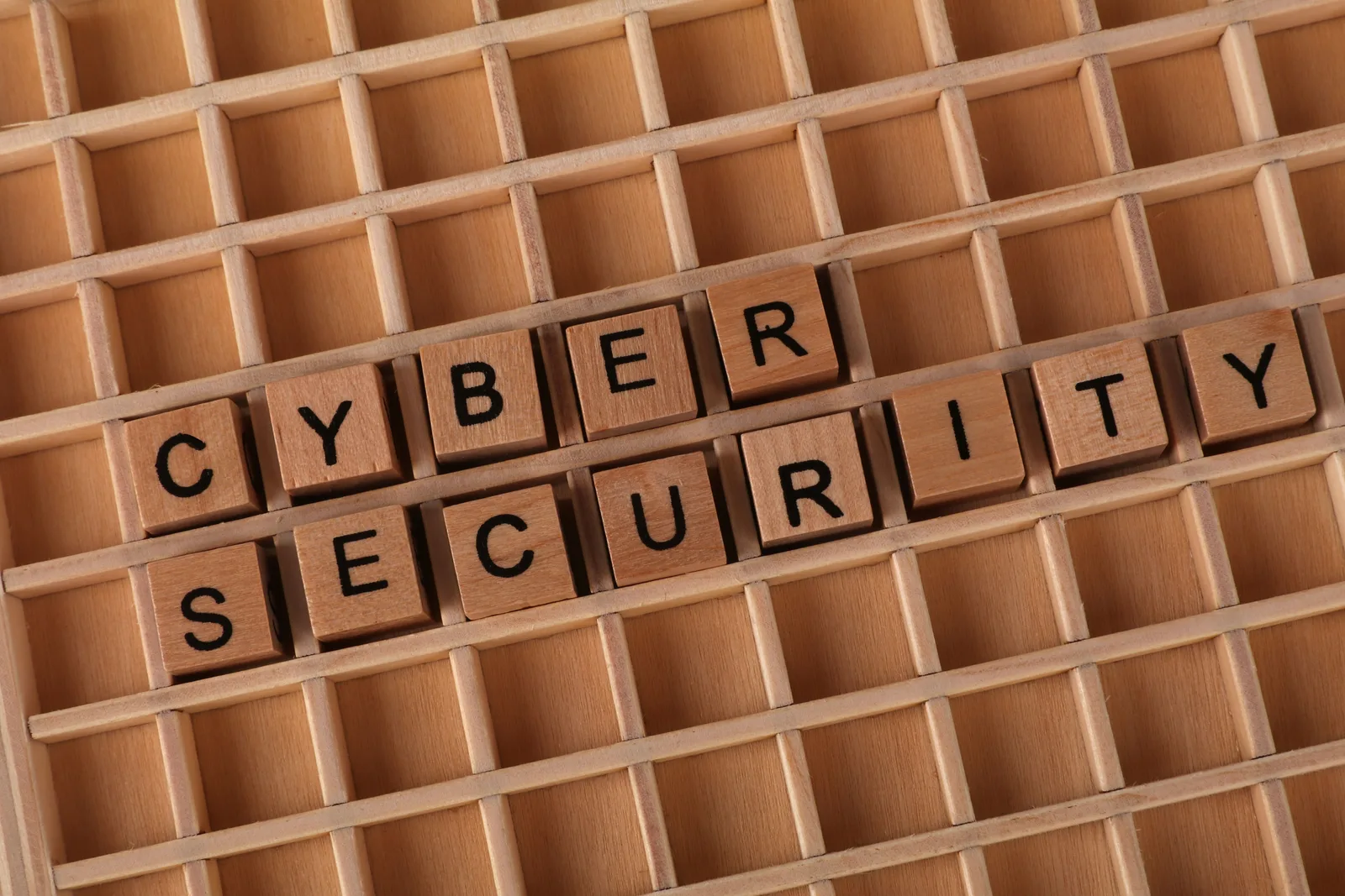 Holzbuchstaben in den Fächern eines Setzkastens bilden einen Begriff zum Thema IT-Sicherheit. Die Aufnahme dient als Symbolbild für die Absicherung von Informationssystemen und digitalen Netzwerken.