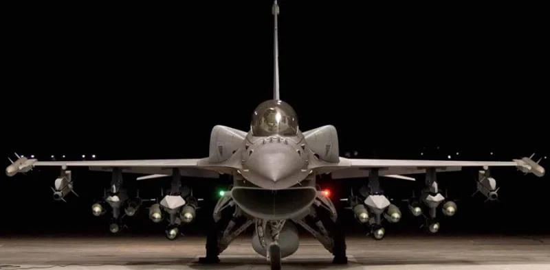 Lockheed Martin F-16 Fighting Falcon mit Außenlasten und konformalen Kraftstofftanks in der Frontalansicht bei Nacht