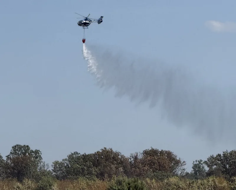 Ein Löschhubschrauber kreist über der betroffenen Waldfläche bei Swisttal-Buschhoven und tankt nach jeder Runde neues Wasser.