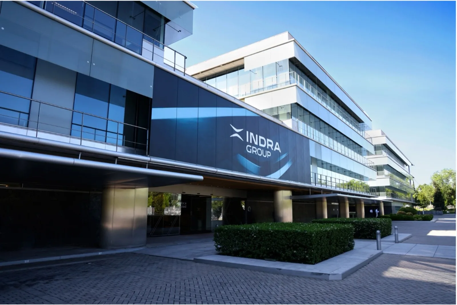 Moderne Glasfassade des Bürogebäudes der Indra Group mit Firmenlogo an der Front