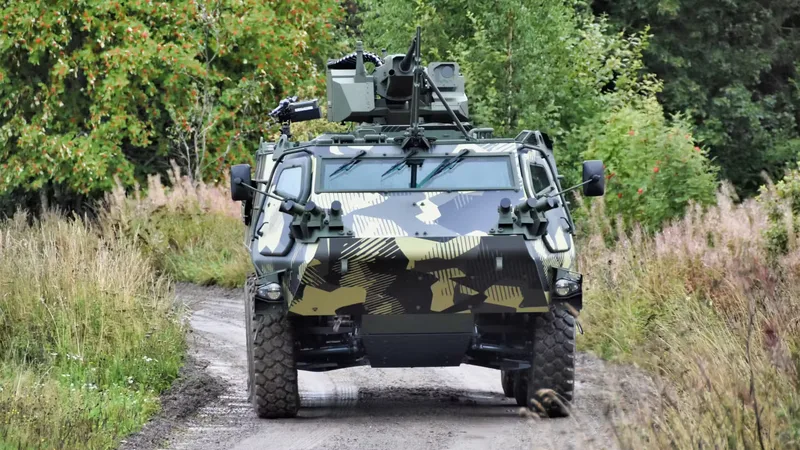 Gepanzertes Radfahrzeug Patria 6x6 mit Tarnlackierung und Waffenstation auf einem unbefestigten Waldweg