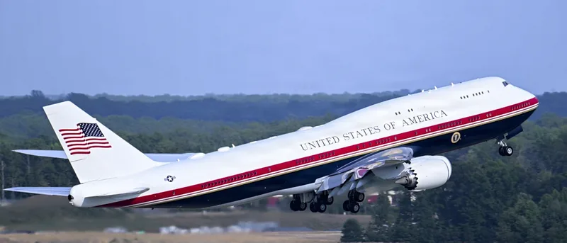 Boeing 747-8 als US-Regierungsflugzeug VC-25B im Steigflug mit rot-weiß-blauer Lackierung und US-Präsidentensiegel am Rumpf