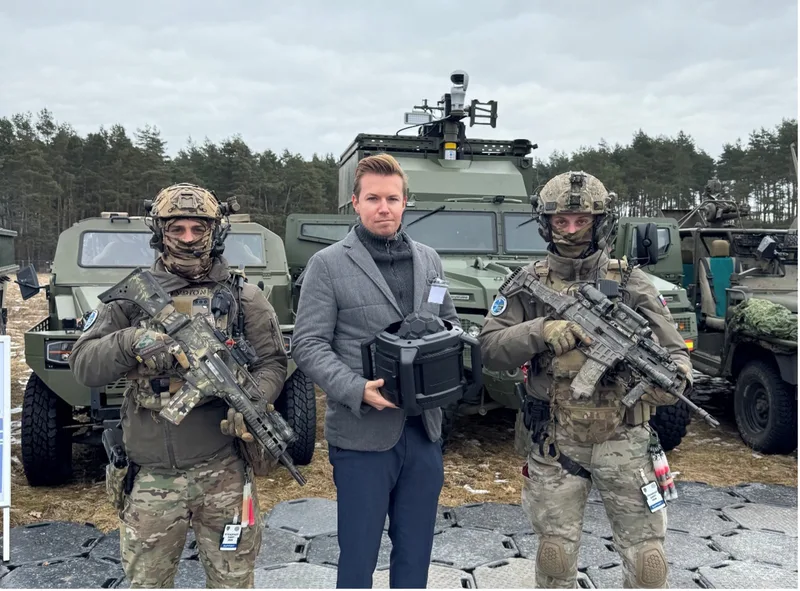 Vertreter des Herstellers Arcani präsentiert während der NATO-Übung Steadfast Dart in Bergen einen Sensor vor zwei Soldaten und Militärfahrzeugen