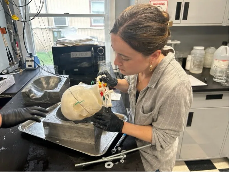 Biomedizintechnikerin Ella Willetts gießt im Labor Gelatine in ein mit Sensoren bestücktes transparentes Kopfmodell zur Simulation