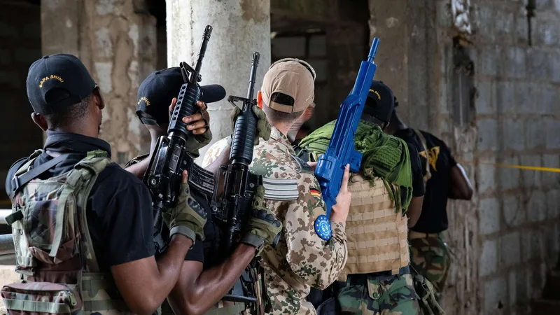 Bundeswehrsoldat in Tropentarn und ghanaische Sicherheitskräfte bei einer taktischen Übung mit M4-Karabinern in einem Rohbau