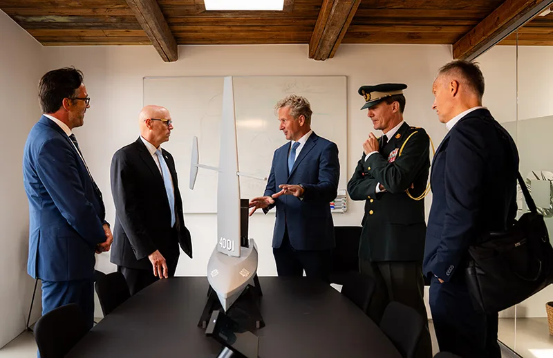 Militäroffizier und Personen betrachten ein Modell eines unbemannten Saildrone-Oberflächenfahrzeugs während einer Präsentation