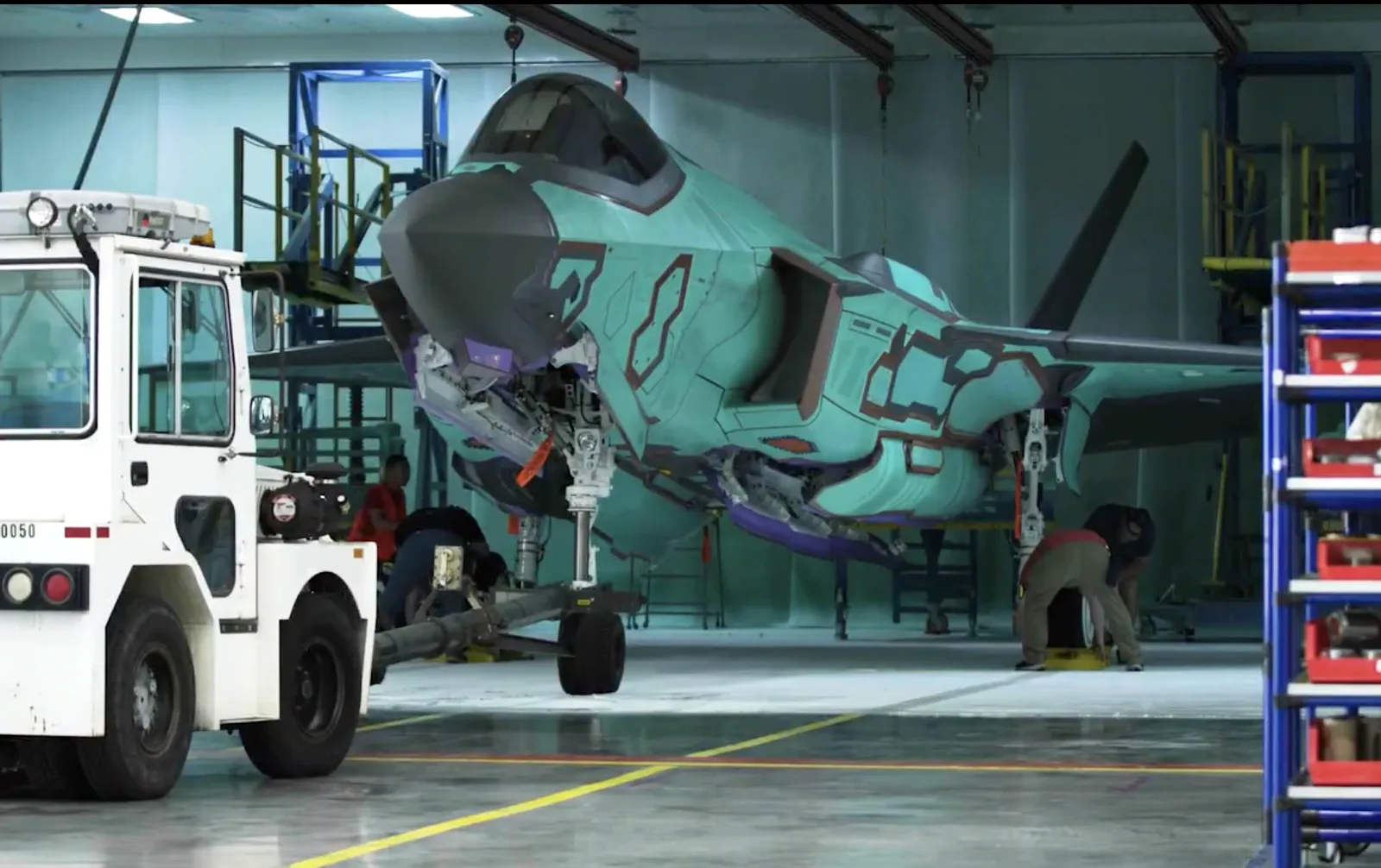 Deutsche F-35 im Video: So sieht der erste Tarnkappenjet aus. Lockheed Martin F-35 in grüner Schutzgrundierung mit gekoppeltem Schleppfahrzeug in einer Montagehalle während Wartungsarbeiten