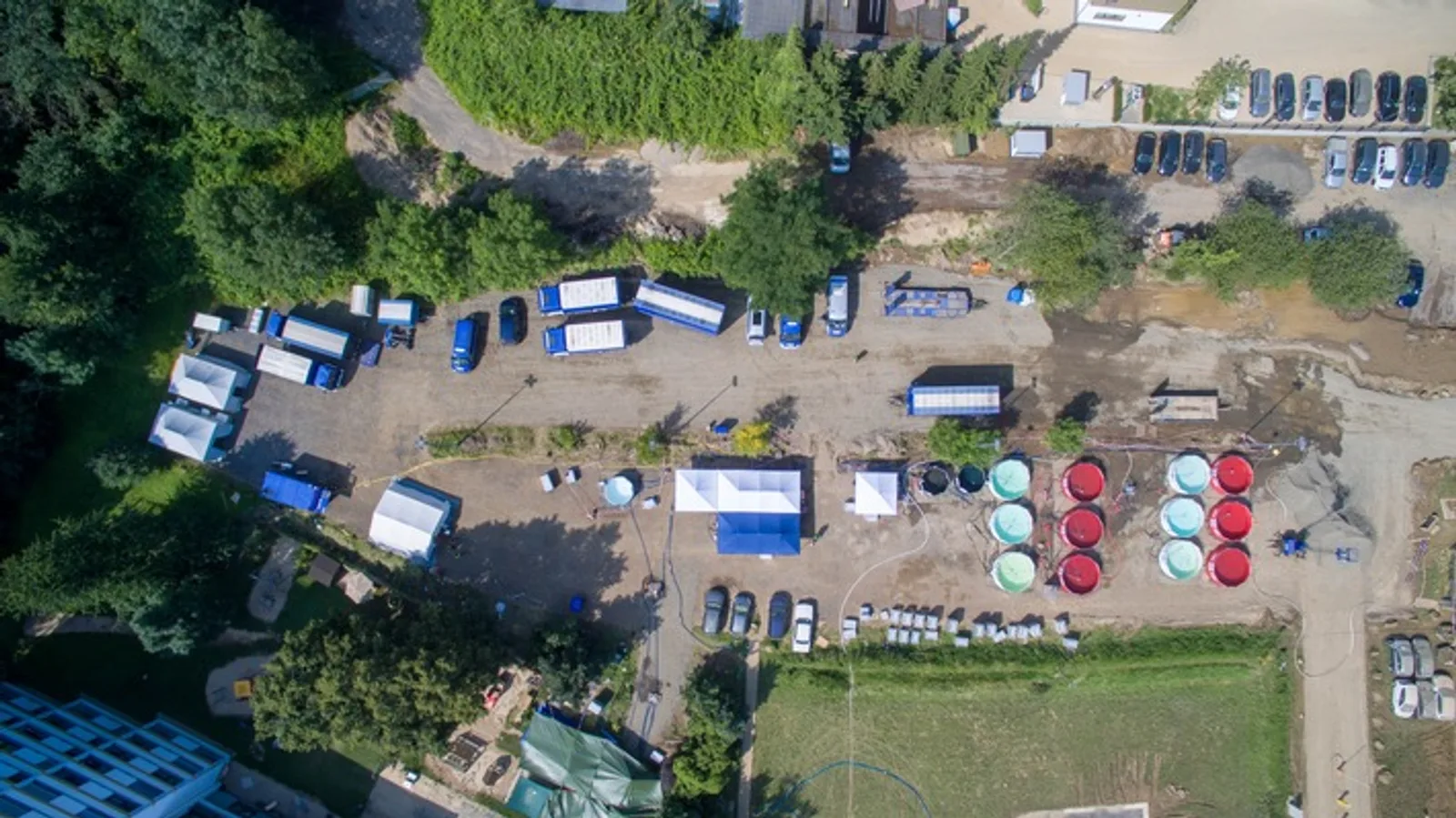 THW: Luftaufnahme einer THW-Station zur Trinkwasseraufbereitung mit blauen Einsatzfahrzeugen, Zelten und kreisförmigen Wasserbecken