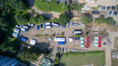 THW: Luftaufnahme einer THW-Station zur Trinkwasseraufbereitung mit blauen Einsatzfahrzeugen, Zelten und kreisförmigen Wasserbecken