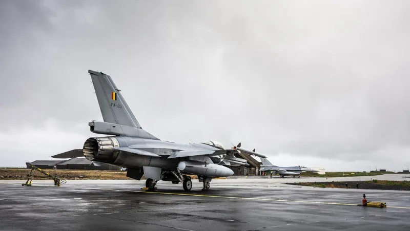 Zwei F-16 Kampfflugzeuge der belgischen Luftstreitkräfte auf einem nassen Rollfeld, im Vordergrund die Heckansicht der FA-103