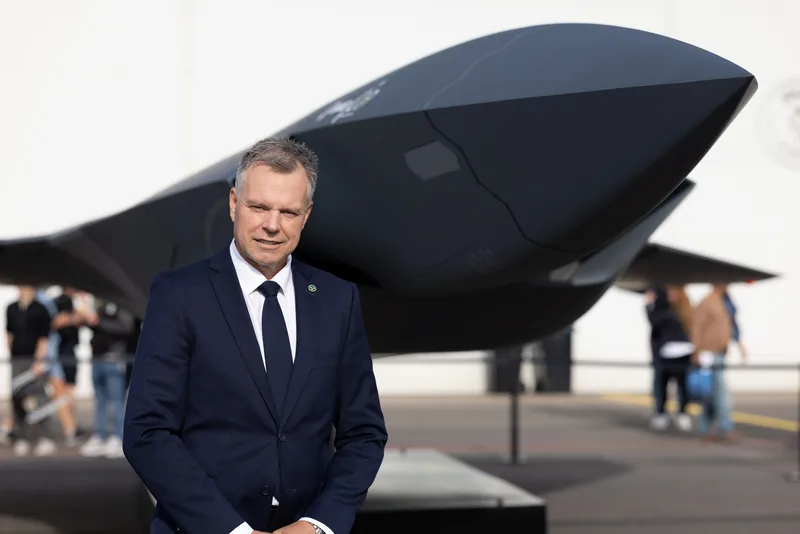 Micael Johansson, CEO von Saab, steht vor einem Modell eines zukünftigen Kampfflugzeugs auf einem Freigelände