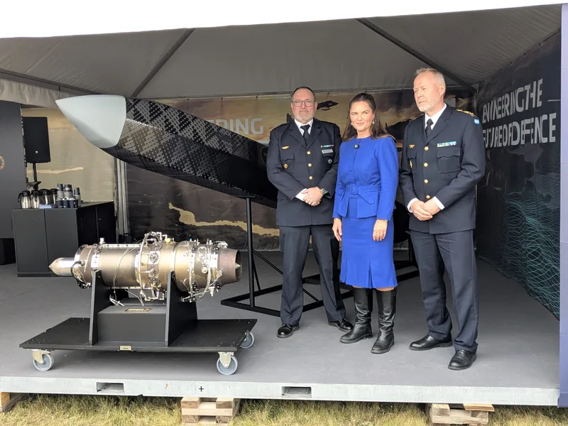 Schwedischer Offizier und zwei Personen neben einer Drohne und einem Gasturbinentriebwerk in einem Ausstellungszelt