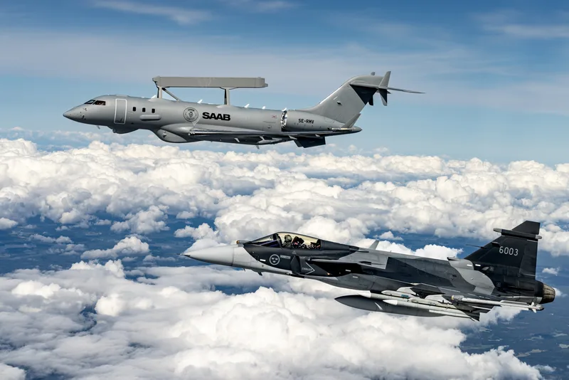 Saab GlobalEye Frühwarnflugzeug und Saab JAS 39 Gripen E Kampfflugzeug im Formationsflug über einer Wolkendecke
