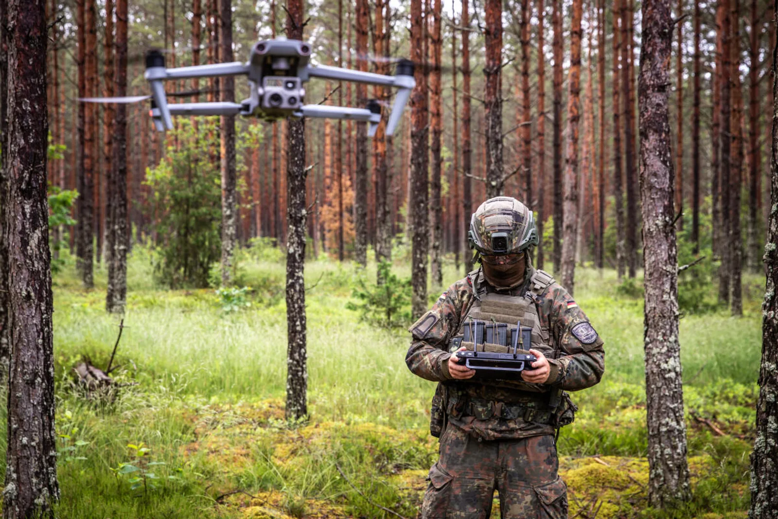Software: Bundeswehr-Soldat in Flecktarn steuert eine DJI Mavic 3 Aufklärungsdrohne in einem Waldgebiet