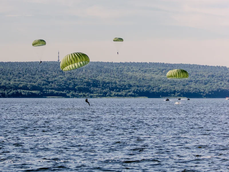 Fallschirmspringer der Bundeswehr landen mit Rundkappenfallschirmen während eines Wassersprungdienstes in einem Gewässer