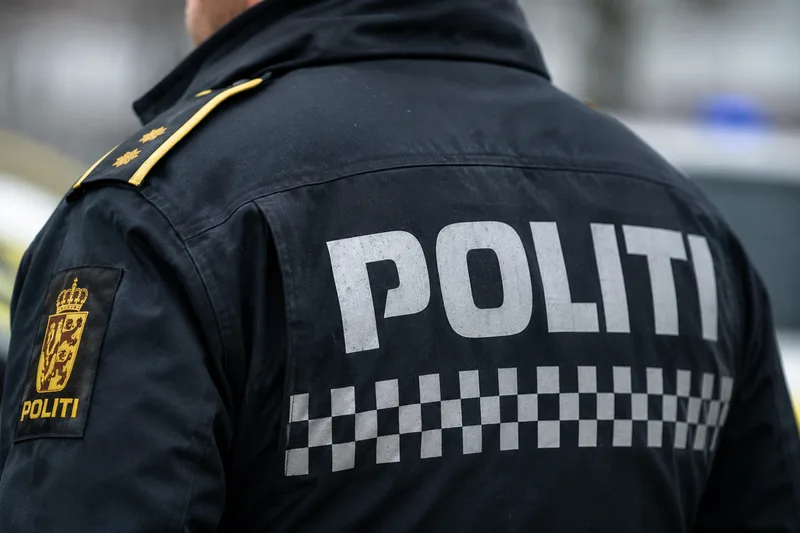 Polizei: Rückansicht eines norwegischen Polizeibeamten in Uniform mit reflektierendem Politi-Schriftzug und Ärmelwappen auf der Einsatzjacke