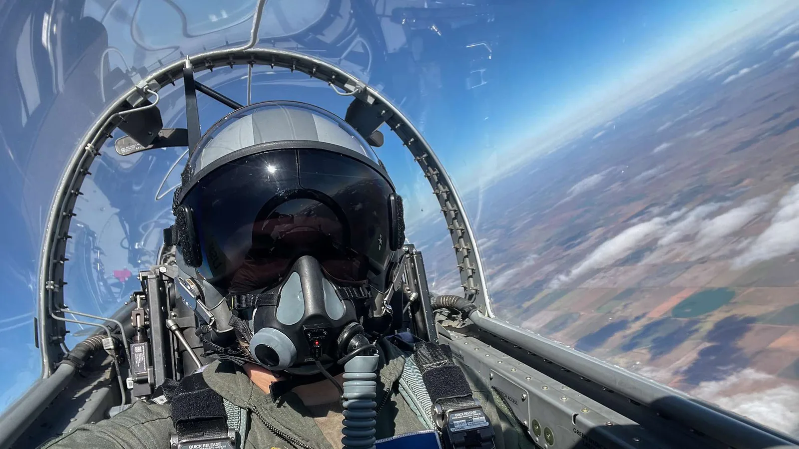 Um Pilot oder Pilotin eines Kampfjets der Bundeswehr zu werden, muss zunächst die fliegerische Erstbefähigung erlangt werden. Das übernimmt ab kommendem Jahr Lufthansa Aviation Training. Pilotin Bea Gabriel der Luftwaffe mit Fliegerhelm und Sauerstoffmaske im Cockpit eines Militärflugzeugs über der Erdoberfläche