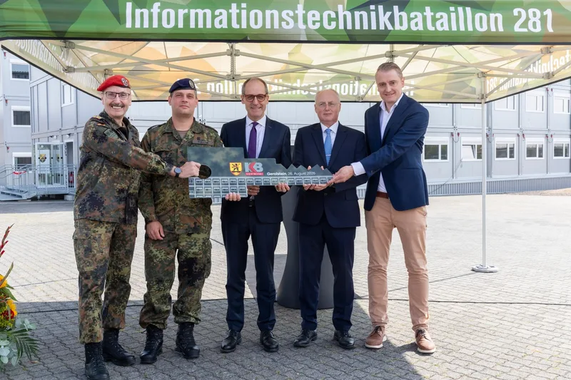 Soldaten der Bundeswehr und Vertreter von KB Container halten einen symbolischen Schlüssel vor neuen Containerbauten in Gerolstein