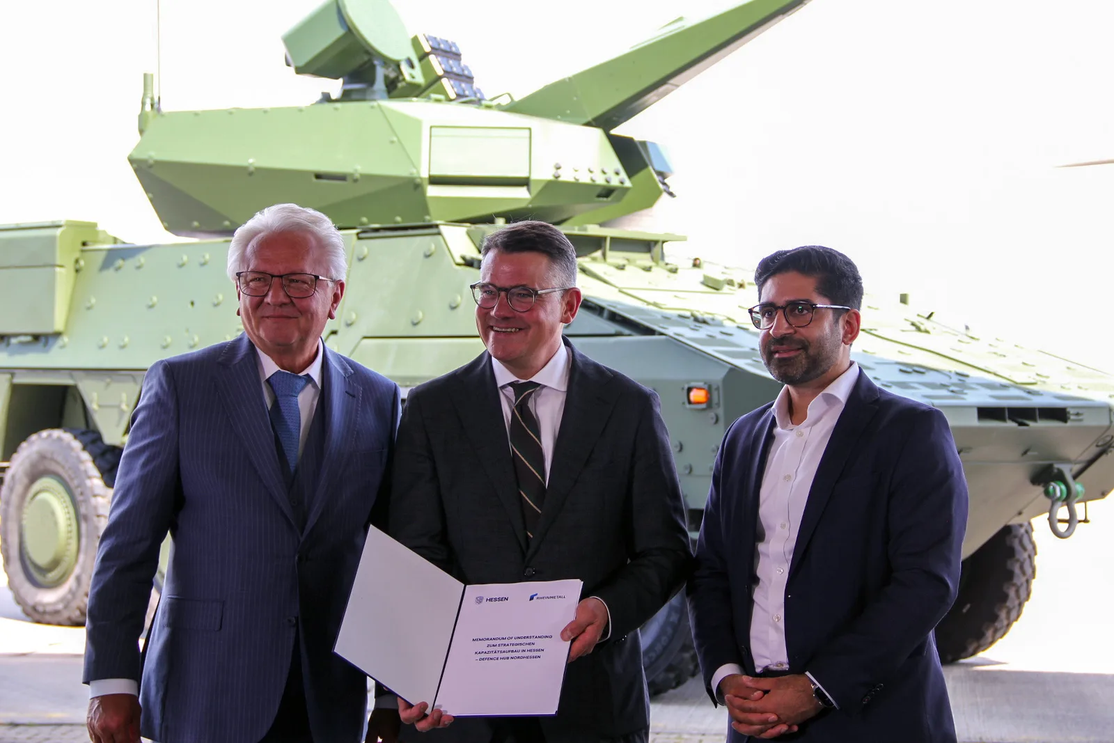 Vertreter der hessischen Landesregierung und Rheinmetall präsentieren eine Absichtserklärung vor einem Boxer-Radpanzer mit Skyranger