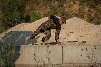 Soldat in Gore-Einsatzbekleidung überwindet während einer Ausbildung auf einem Übungsgelände eine Betonbarriere