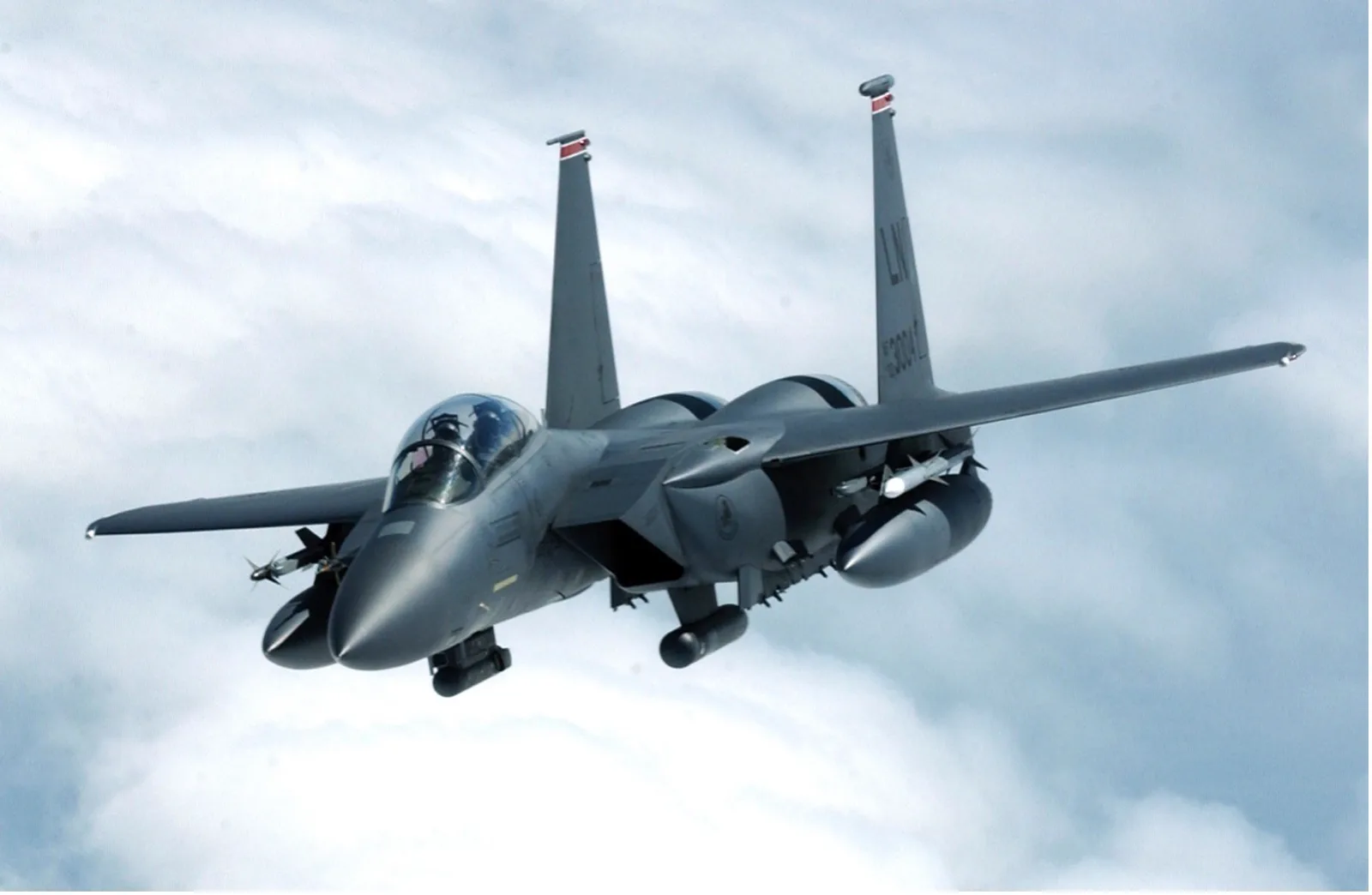 Boeing F-15E Strike Eagle der US Air Force mit Zusatztanks und Lenkwaffen im Flug über einer Wolkendecke