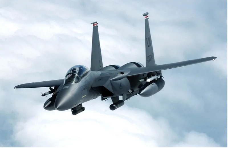 Boeing F-15E Strike Eagle der US Air Force mit Zusatztanks und Lenkwaffen im Flug über einer Wolkendecke