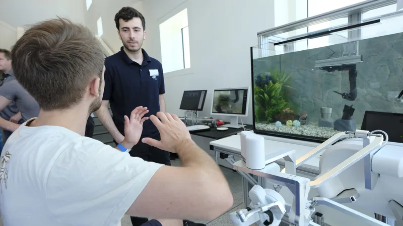 Besucher testet am DLR-Stand ein haptisches Eingabegerät zur Fernsteuerung eines Roboterarms in einem Aquarium