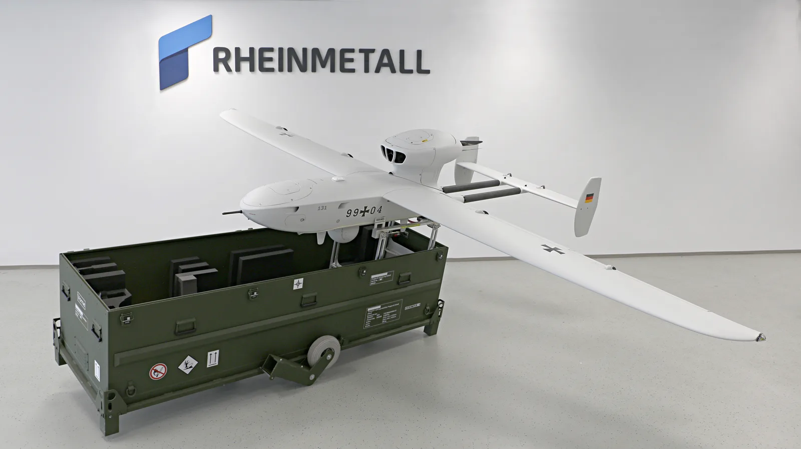 Unbemanntes Aufklärungssystem LUNA NG der Bundeswehr auf einem Transportbehälter vor einer Rheinmetall-Logo-Wand
